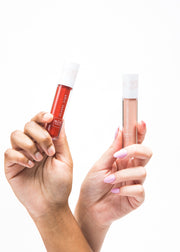 two hands respectively holding lip gloss in different shades