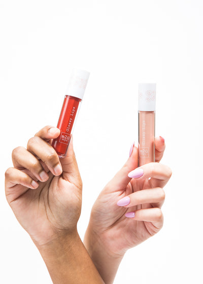 two hands respectively holding lip gloss in different shades