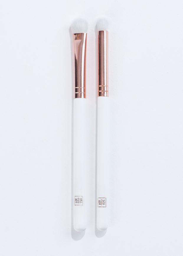 two white and rose gold eyeshadow brushes with different bristle shapes lying next to each other