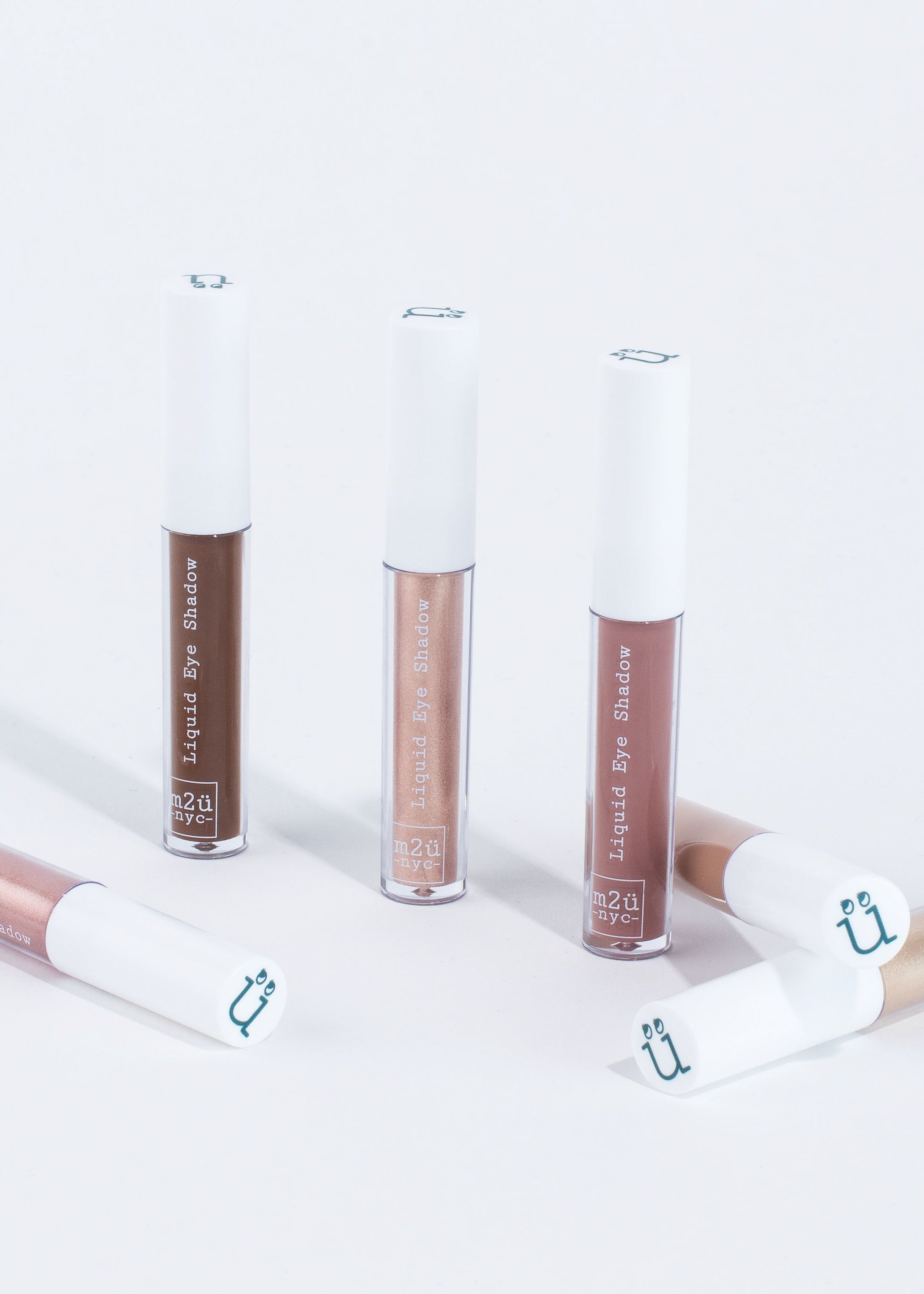 a collection of six liquid eyeshadow in different shades standing and lying down 