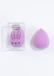 two egg-shaped purple makeup blending sponge, one in a clear box with rabbit illustration on and one with no box 