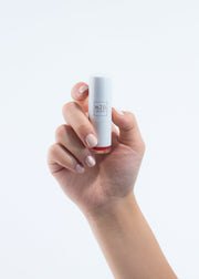 hand holding a vegan, cruelty free moisturizing lipstick in white packaging