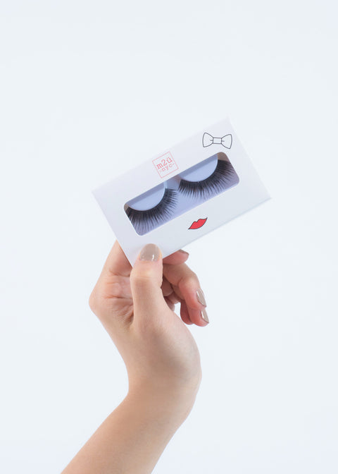 hand holding a pair of false eyelashes in a white box with red lips